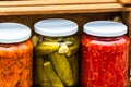 Wooden crate with glass jars with variety of canned vegetables isolated