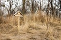 Wooden cross on an abandoned grave surrounded by old trees and grass