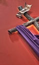 A wooden cross affixed to the red wall, with a purple cloth wrapped around it, symbolizes Christ\'s passion and resurrection Royalty Free Stock Photo