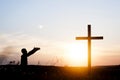 Wooden cross against the sky. The silhouette of the cross. A man is praying with his hands up. Motiveva on her knees. Sunset Royalty Free Stock Photo