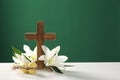 Wooden cross, crown of thorns, Easter eggs and blossom lilies on table against color background Royalty Free Stock Photo