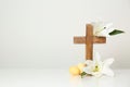 Wooden cross, Easter eggs and blossom lilies on table against light background Royalty Free Stock Photo