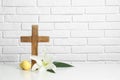 Wooden cross, Easter eggs and blossom lily on table against brick wall Royalty Free Stock Photo