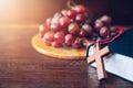 Wooden cross lean on holy bile over grape on wood plate