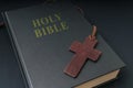 Wooden cross next to Holy Bible