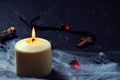 Halloween wooden cross lying next to a burning candle on a web with spiders and bats on a black background. horizontal