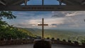 Wooden cross with a quote from the Bible on a tower overlooking a beautiful landscape with a rainbow