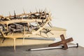 A wooden cross thorn crown with nail and Bible on a light background