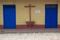 Wooden cross between two blue wooden doors on brick walls in a suburban area in Cuba Royalty Free Stock Photo