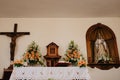 Wooden crucifix cross, flowers, and other saint icons in catholic church in Spain