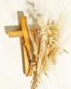 Wooden crucifixion with bouquet of wheat and rye on light background