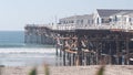 Wooden Crystal pier on piles with white cottages, California ocean beach, USA.