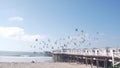 Wooden Crystal pier on piles with white cottages, California ocean beach, USA.