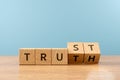 Wooden cube block flip over word TRUTH to TRUST on wood table, 3D render