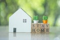 Wooden cube block with STAY HOME with miniature cactus and placed near wood home. Quarantine against coronavirus covid-19 Royalty Free Stock Photo