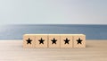 Wooden cube five black star review on blur sea with the sky background. Service rating, satisfaction concept. reviews and comments Royalty Free Stock Photo