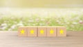 Wooden cube five yellow star review on blur field of flowers background. Service rating, satisfaction concept. reviews and