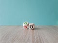 Wooden cube flipping for change between go and no. Beautiful blue background.