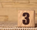 Wooden cube with the number three on a beige background Royalty Free Stock Photo