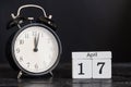 Wooden cube shape calendar for April 17 with black clock.