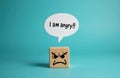 Wooden cube shows angry face with speech bubble saying I am angry. Simple object represents negative emotion and communication. Royalty Free Stock Photo