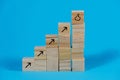 Wooden cubes arranged as stair steps with arrows pointing upwards and a thumb up symbol on the top, business growth and management