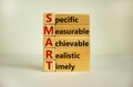 Wooden cubes and blocks with words `SMART, specific measurable achievable realistic timely`. Beautiful white background, copy