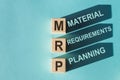 Wooden cubes building word MRP - Abbreviation of Material requirements planning on light blue background