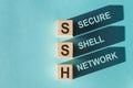 Wooden cubes building word SSH - abbreviation Secure Shell Network on light blue background