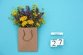 Wooden cubes calendar August 27 and field colorful rustic flowers in craft package on blue background. Greeting card Flat Lay Royalty Free Stock Photo
