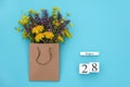 Wooden cubes calendar August 28 and field colorful rustic flowers in craft package on blue background. Greeting card Flat Lay Royalty Free Stock Photo