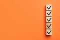 Wooden cubes with check marks on orange background, top view. Space for text