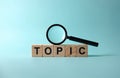 Wooden cubes compose topic text on blue background. Magnifying glass over word. Photo presents problem study, keyword analysis, Royalty Free Stock Photo