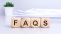 The wooden cubes displaying the text 'FAQS' against a light gray background signify a focus on blogging or