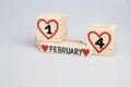 Wooden cubes with handwritten one and four inside red hearts, February month.