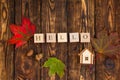 Wooden cubes with HELLO inscription on a wooden dark background with colorful maple leaves and acorn