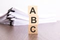 wooden cubes with letters ABC arranged in a vertical pyramid, stack white paper on background, business concept, ABC - Royalty Free Stock Photo