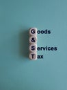 Wooden cubes with letters Goods and services tax on blue background. State financial policy to regulate tax collection rules and