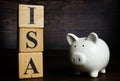 Wooden cubes with letters and piggy bank ISA Individual Savings Account.