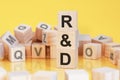 wooden cubes with letters R and D arranged in a vertical pyramid, yellow background