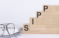 Wooden cubes with letters SIPP on the white table with keyboard and glasses