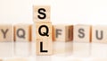 wooden cubes with letters SQL arranged in a vertical pyramid, white background, reflection from the surface of the table Royalty Free Stock Photo