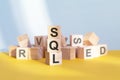 Wooden cubes with letters SQL arranged in a vertical pyramid, yellow background Royalty Free Stock Photo