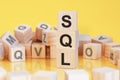 wooden cubes with letters sql arranged in a vertical pyramid, yellow background Royalty Free Stock Photo