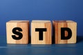 Wooden cubes with letters STD sexually transmitted diseases on blue table Royalty Free Stock Photo