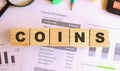 Wooden cubes with letters on the table in the office. Text COINS. Financial concept.