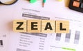 Wooden cubes with letters on the table in the office. Text ZEAL.