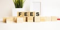 Wooden cubes with letters on a white table. The word is FEES. White background Royalty Free Stock Photo