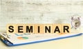 Wooden cubes lie on a folder with financial charts on a gray background. The cubes make up the word SEMINAR.