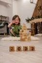 Wooden cubes with the numbers 2022 stand on the floor in a row. Background of a blurred happy girl Royalty Free Stock Photo